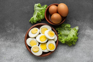Plate with halves of boiled chicken eggs and fresh lettuce on black and white background