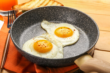 Frying pan with tasty fried eggs on wooden table, closeup