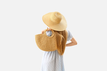 Fashionable woman in stylish hat holding rattan handbag on light background