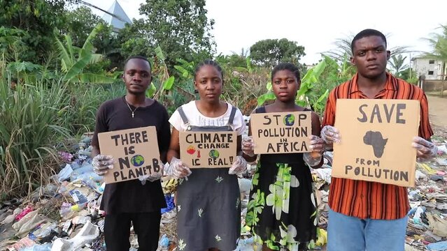 a group of Protestants in Africa in front of an illegal open-air landfill with signs to raise awareness.
