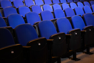 Close up shot of interior of cinema auditorium with lines of blue chairs. Horizontal shot