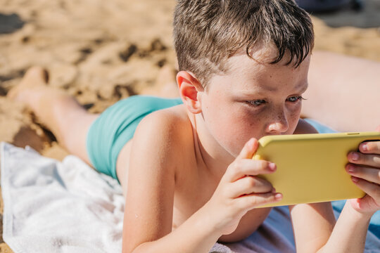 Boy browsing smartphone on beach