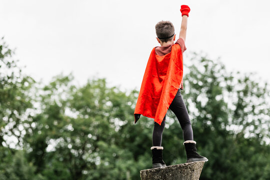 Anonymous superhero in hedgehog mask in park with arms raised with clenched fist