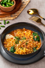 Indomie Kuah Telur is Indonesia Instant noodle soup served on black bowl with boiled pouch egg and chili. 