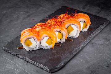 delicious sushi rolls on a black stone background