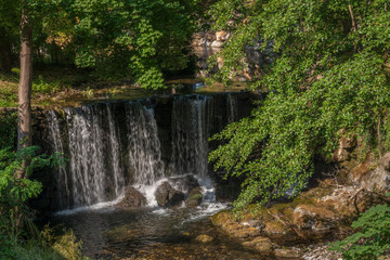 Scenic summer landscape of waterfall amidst green foliage in the Boulzane river valley, Gincla, Aude, France