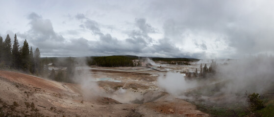Hot spring Geyser with colorful water in American Landscape. Cloudy Sky. Yellowstone National Park, Wyoming, United States. Nature Background Panorama