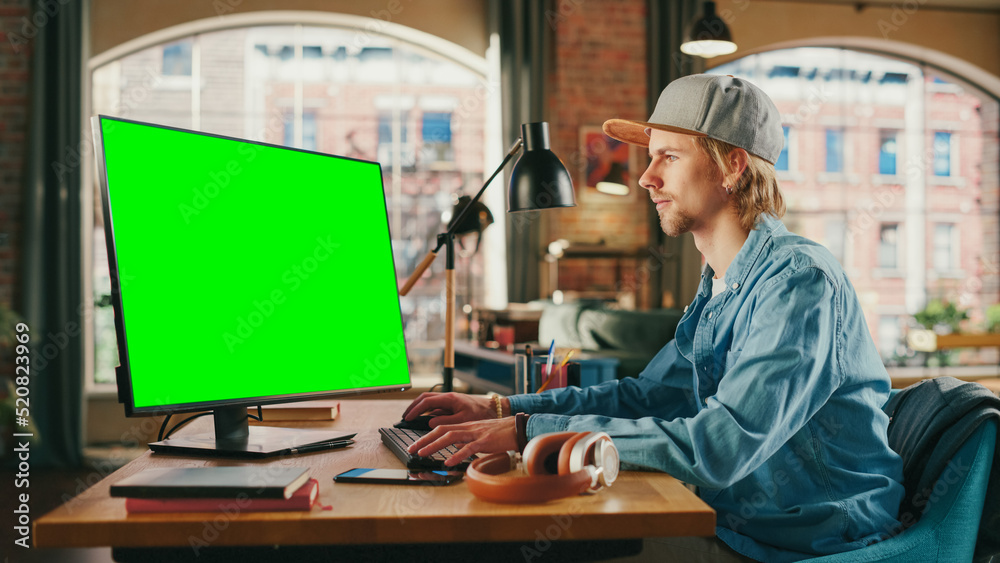 Fototapete young handsome man working from home on desktop computer with green screen mock up display. student 