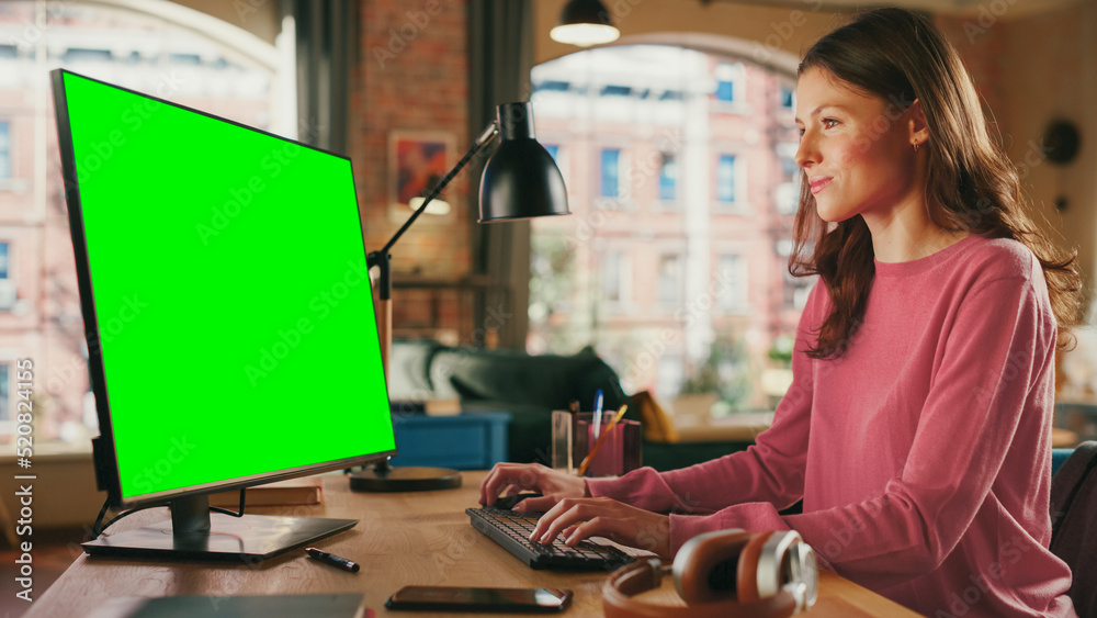 Poster young pretty female working from home on desktop computer with green screen mock up display. creativ