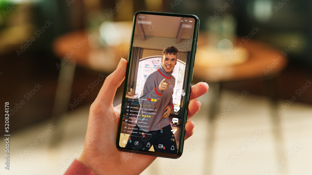 Poster feminine hand holding a smartphone with social media application on display. female in casual clothe