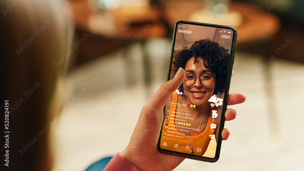 Poster feminine hand holding a smartphone with social media application on display. female in casual clothe