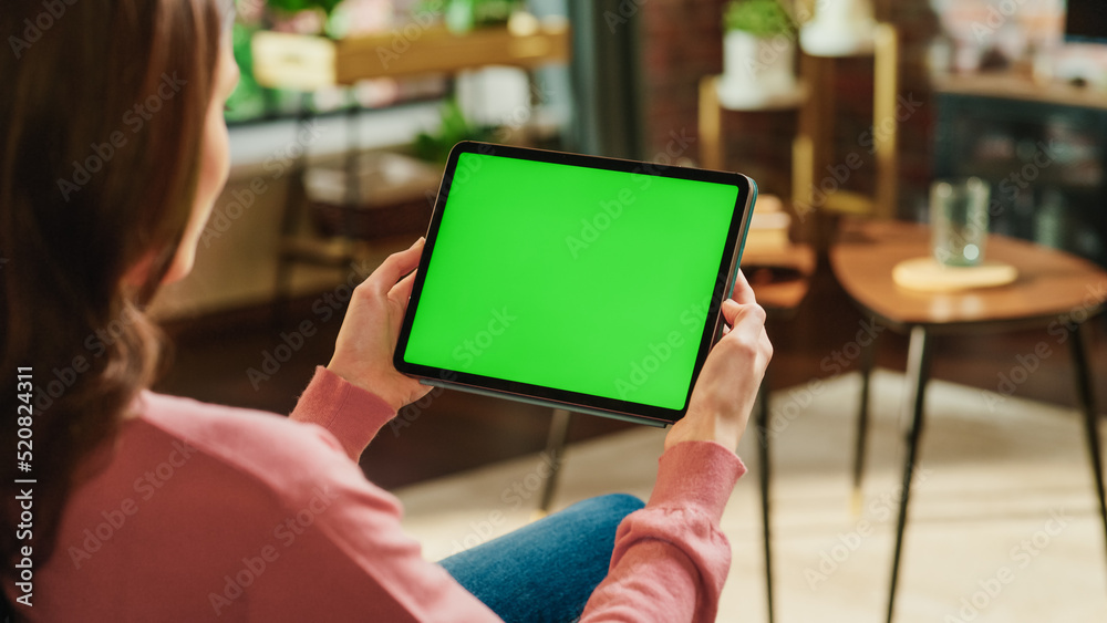 Poster female holding tablet computer with green screen mock up display. woman relaxing at home, watching v