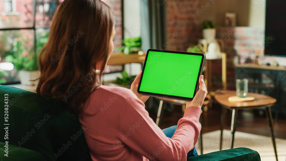Poster female holding tablet computer with green screen mock up display. woman relaxing at home, watching v