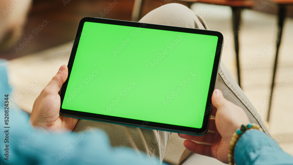 Poster Young Man Scrolling and Tapping on Content on Tablet Computer with Green Screen Mock Up Display. Male Relaxing at Home, Reading Social Media Posts on Mobile Device. Close Up Over the Shoulder Photo.