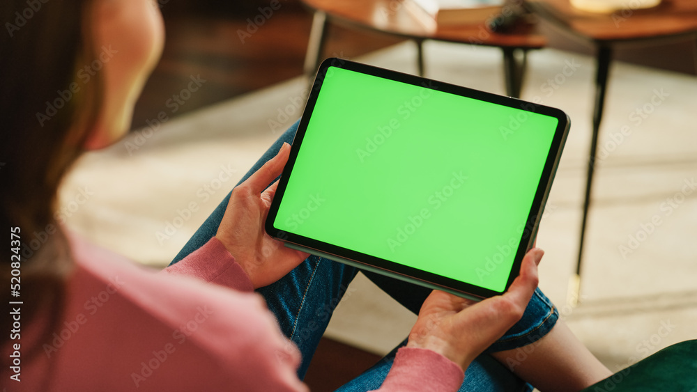 Poster female holding tablet computer with green screen mock up display. woman relaxing at home, watching v
