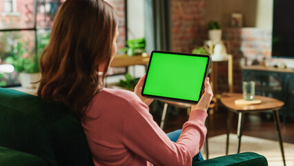 Female Holding Tablet Computer with Green Screen Mock Up Display. Woman Relaxing at Home, Watching...