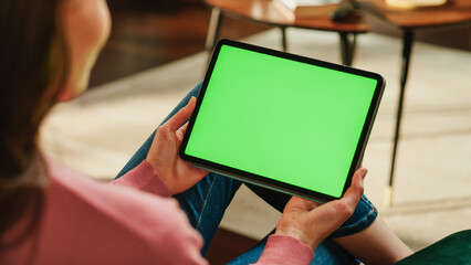 Female Holding Tablet Computer with Green Screen Mock Up Display. Woman Relaxing at Home, Watching...