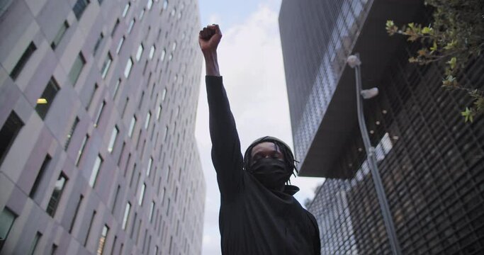 Young african american black man rasises his fists up in solidarity justice. 