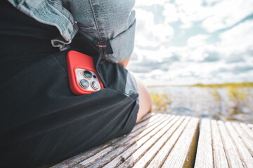 Woman puts mobile phone in jeans pocket on gray light background. Isolation, space for text