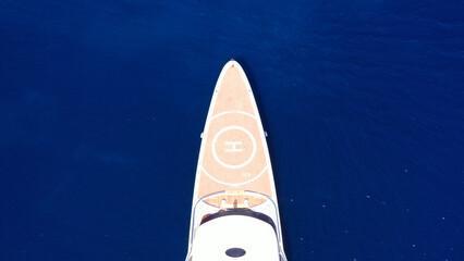Aerial drone top down photo of luxury mega yacht with wooden deck and helipad anchored in deep blue...
