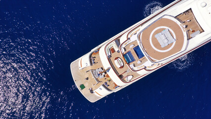 Aerial drone top down photo of luxury mega yacht with wooden deck and helipad anchored in deep blue...