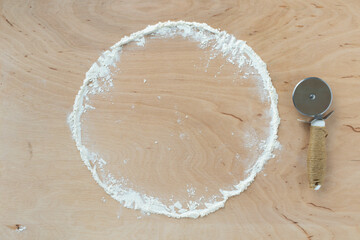 flour powder sprinkled in a circle on cutting board and wooden table background