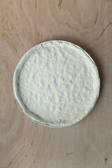 Pizza dough on wooden background, top view