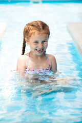 Fototapeta na wymiar A little girl in a pool of blue water. Vacation.