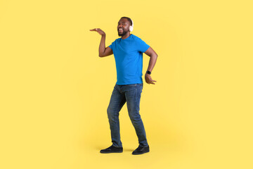 Fototapeta na wymiar Black Guy Listening To Music Wearing Earphones Dancing, Yellow Background