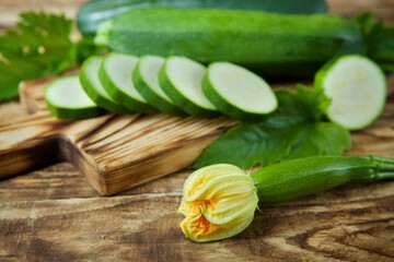 The raw product of zucchini lie on the wooden surface of the table. Ingredients for cooking. Seasonal vegetables.