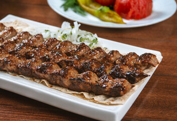 Fast food. Eastern food. Shish kebab, lyulya-kebab. Dishes of oriental cuisine lying in plte and decorated with greens and vegetables, sauces