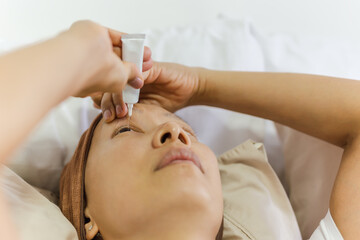 Obraz na płótnie Canvas Asian woman uses eye drops for eye treatment.