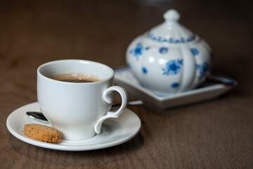 a cup of coffee with cookies and a sugar bowl on the table