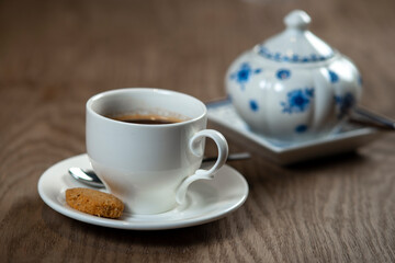 a cup of coffee with cookies and a sugar bowl on the table