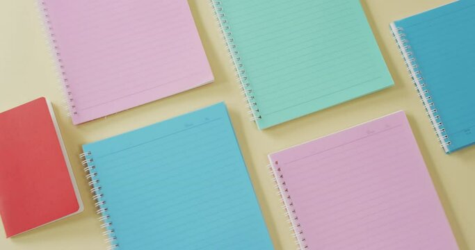 Video of composition with colorful notebooks on yellow surface