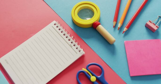 Video of composition of school items with notebook with copy space on pink and blue surface
