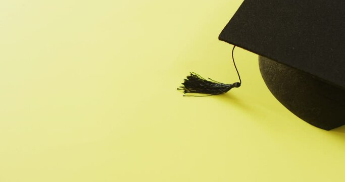 Video of graduation hat lying on yellow background