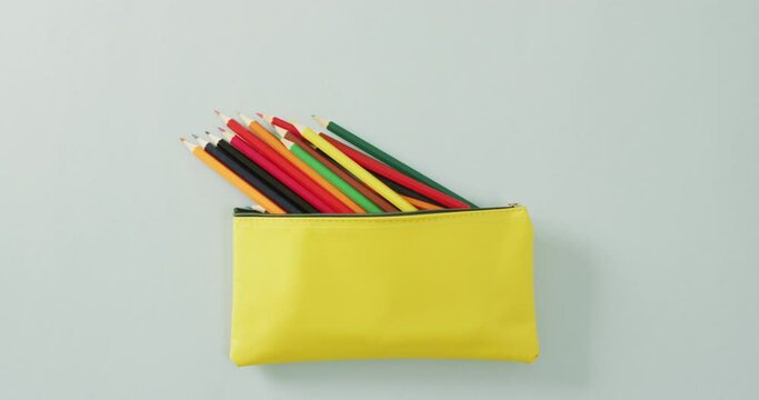 Video of colorful crayons in yellow case on grey background