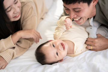 Obraz na płótnie Canvas Family of baby girls Asian fathers and mothers They are doing fun activities on the bed in the house. perfect family concept The love of fathers and mothers for their children the growth of infants