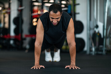 Fototapeta na wymiar Athletic Black Man Making Floor Push Up Exercise While Training In Gym