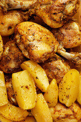 Roasted chicken legs and baked potatoes. Close up view.