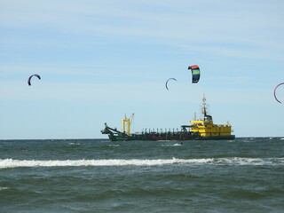 ship in the sea and kitesurfers