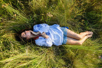 A teenage girl lies in a tall meadow grass.