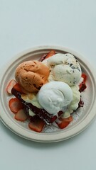 Ice cream waffles, Thai tea flavor, coconut milk and chocolate chips topped with fresh strawberries at a seaside café. Top view.