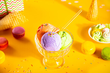 Various colorful ice cream scoops or balls sundae dish with waffle cones, macaroons on yellow...