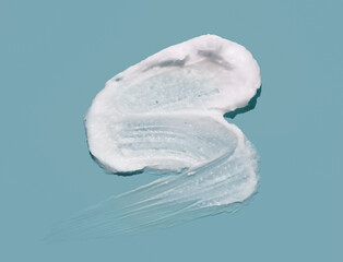 White cosmetic cream lotion swatch smear smudge on blue color background.	