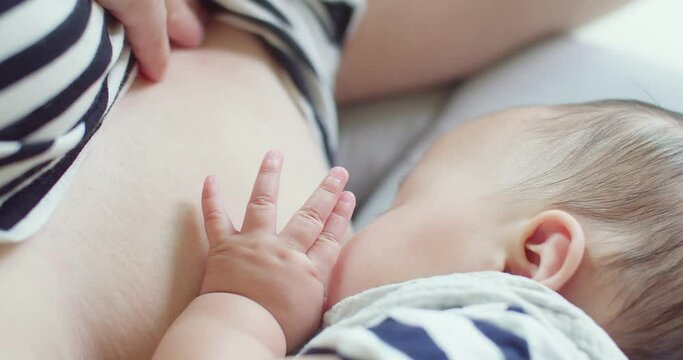 Close up baby hands touch mother breast, mom breastfeeding newborn baby infant nursing and feeding Baby, feeling love in touch, maternity, healthcare, breastfeeding, motherhood, childhood concept	