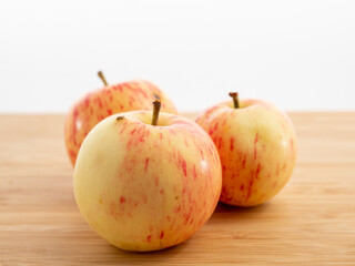 Fresh red apples on a wooden table with a white background.