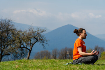 Naklejka na ściany i meble Young man do yoga on the rock peak. Meditation