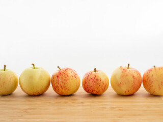 Fresh red apples on a wooden table with a white background.